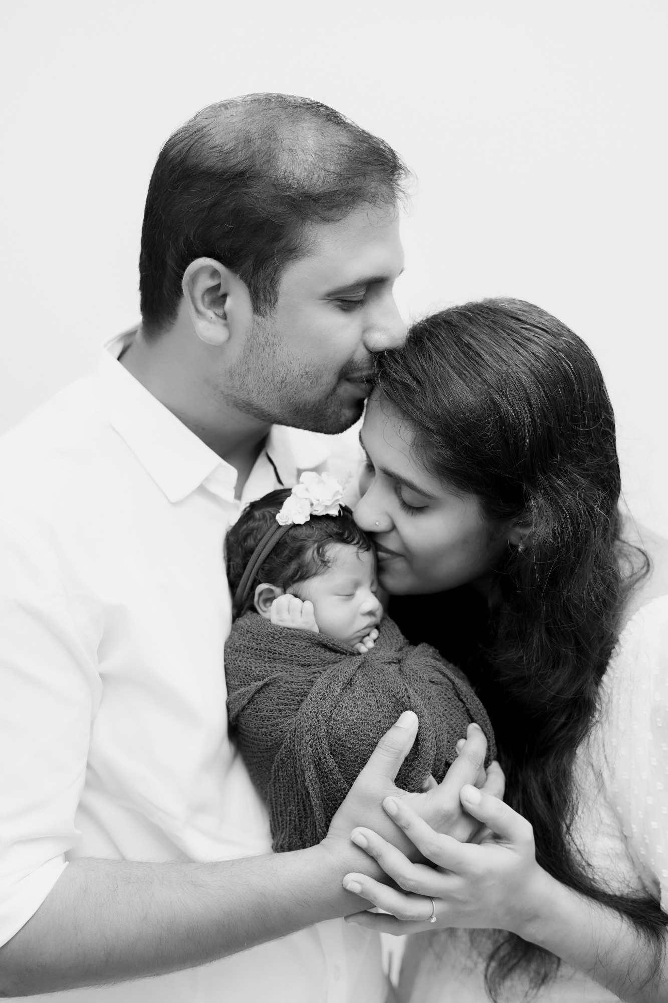 A couple lovingly holds their newborn baby, sharing a tender moment together.